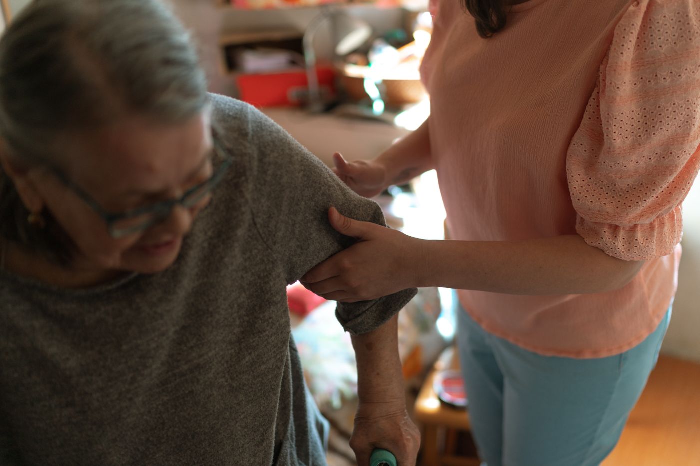 A care worker supporting an older woman with mobility in her own home